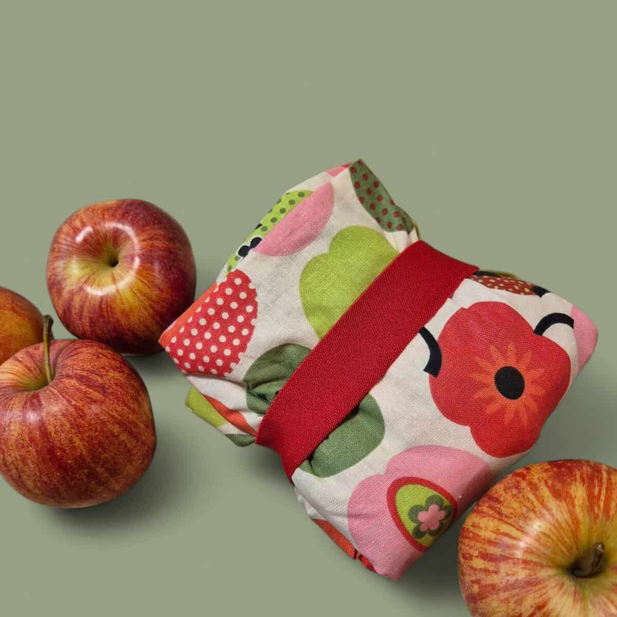 Frisches Frühstücksset mit Äpfeln und buntem Stoffserviette auf grünem Hintergrund.