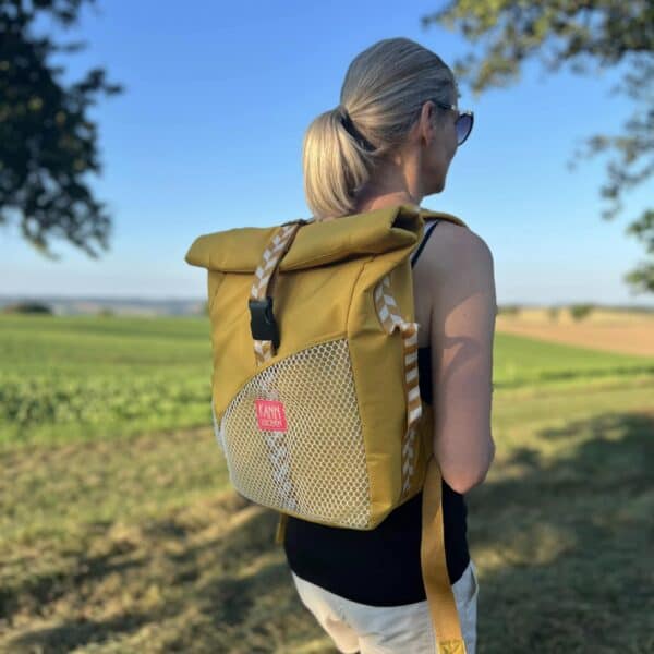Frau mit gelbem Rucksack im Freien, Naturhintergrund, Sonnenlicht.