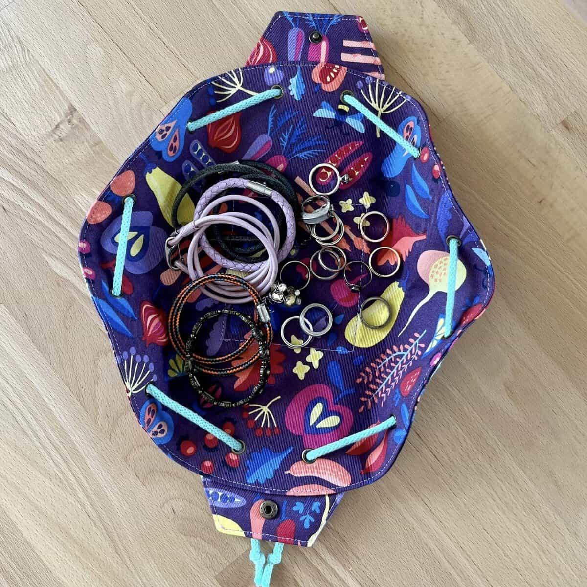 Colorful fabric bag filled with jewelry and accessories, perfect for sewing projects.