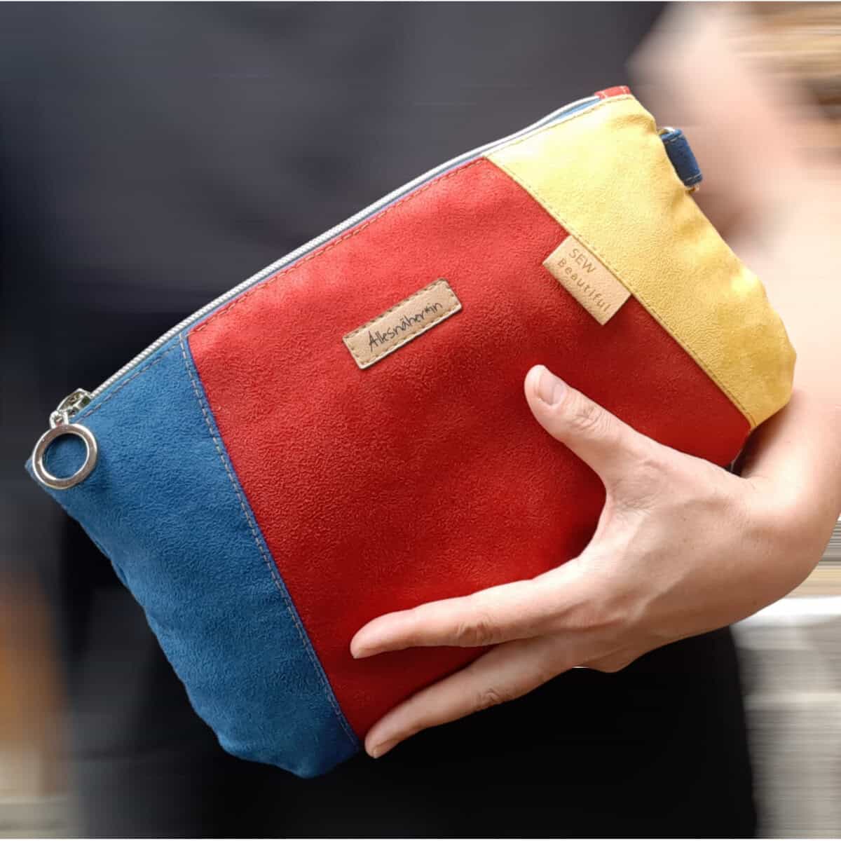Luggage with a colorful, vibrant design that is carried by hand.