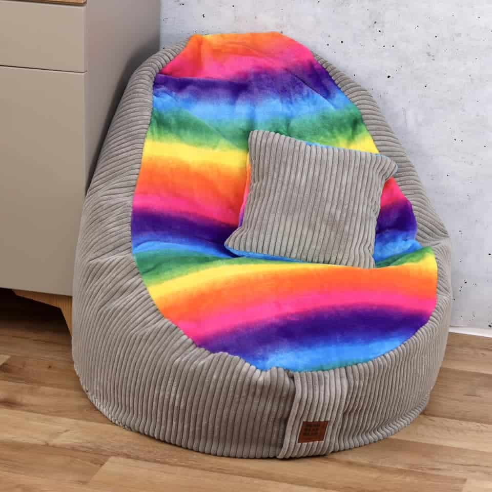 Gemütliches Sitzkissen mit buntem Regenbogen-Design und grauem Kissen auf weichem, gepolstertem Sitz.