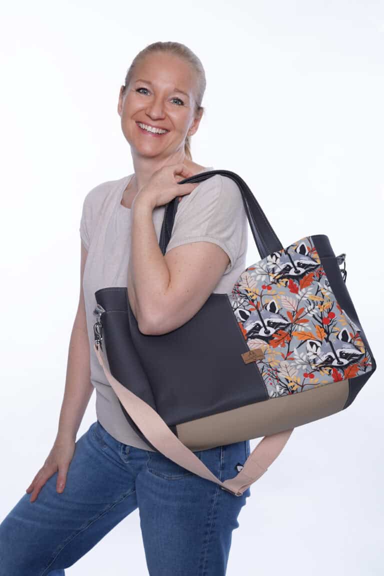 Lächelnde Frau mit stilvoller Tasche vor weißem Hintergrund.