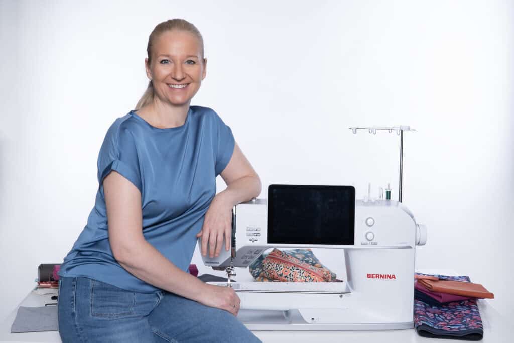 Frau arbeitet mit Nähmaschine, kreative Nähprojekte im Hintergrund.