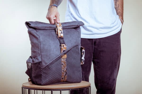 Modischer Rucksack aus grauem Stoff mit braunen Akzenten und Mesh-Taschen.