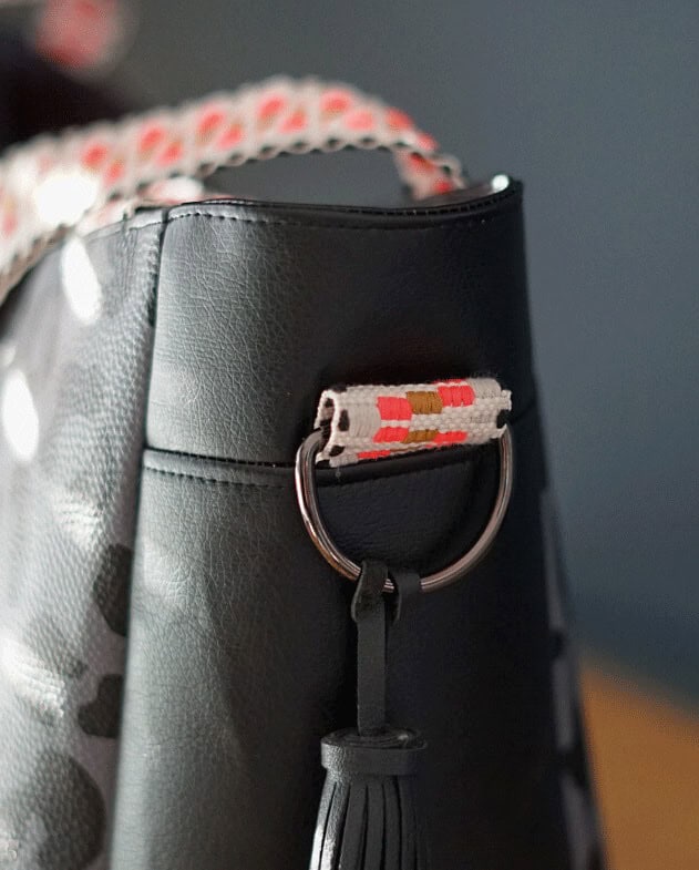 Schwarze Tasche mit dekorativem Schlüsselring und Stoffdetail.