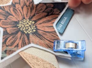 Stoff mit Blumenmuster, Nähklammer und Label für Nähprojekt.