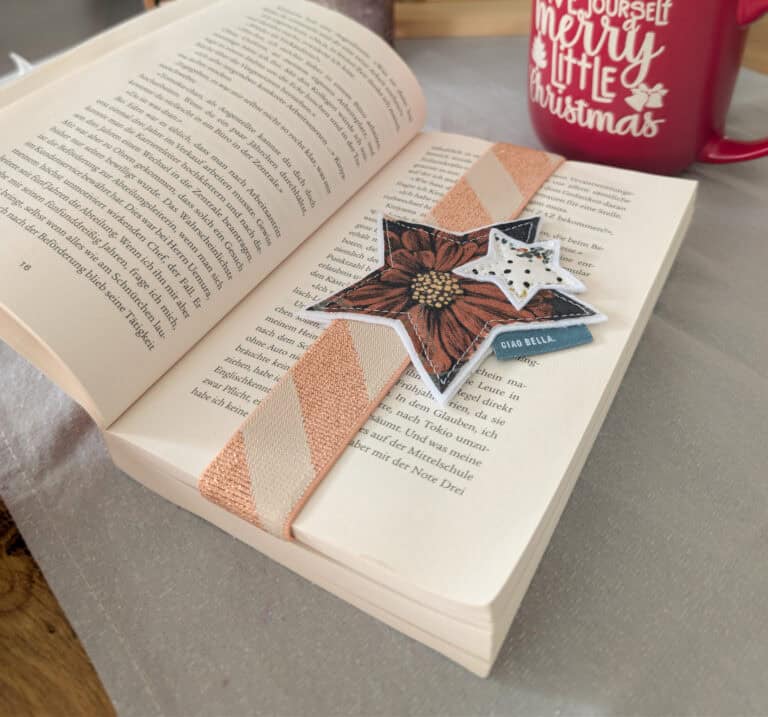 Buch mit Weihnachtsdeko und Lesezeichen aus Stoff und Papier.