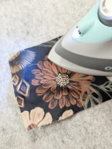 Bügeleisen auf Stoff mit Blumenmuster beim Nähen.