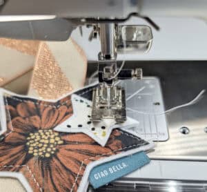 Nähmaschine näht einen Weihnachtsstern aus Stoff mit Blumenmuster.
