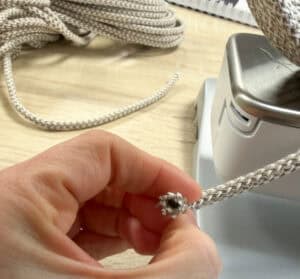 Hand hält Seil zum Nähen eines Körbchens aus Seil.