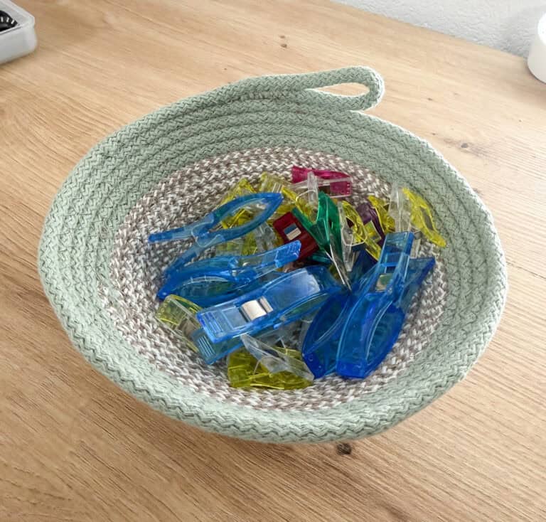 Bunte Kunststoffklammern in einem handgewebten Korb aus Seil.